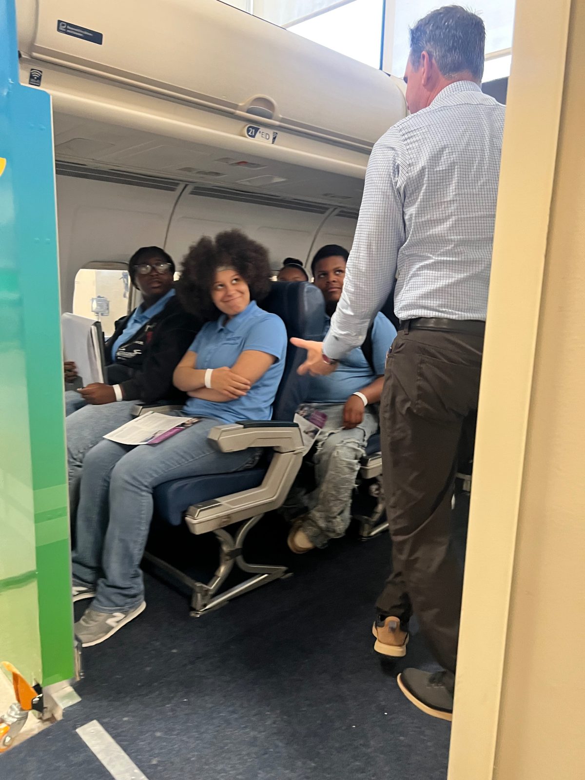 A guest speaker demonstrating the airplane cabin training exhibit for Summer Institute students