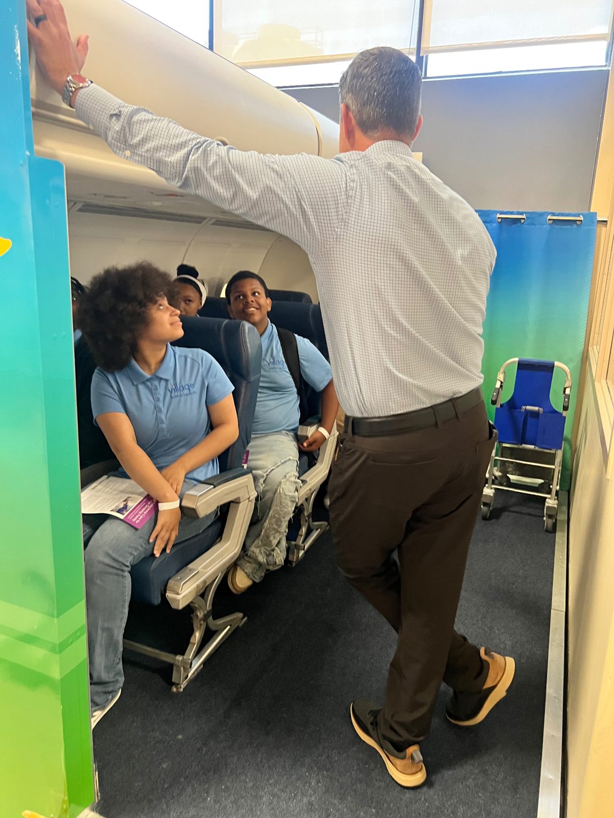 Summer Institute students exploring an airplane cabin training exhibit with a guest speaker